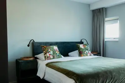 a bedroom with a bed with pillows and a window at Appartement Spoorklokken in Bergen aan Zee