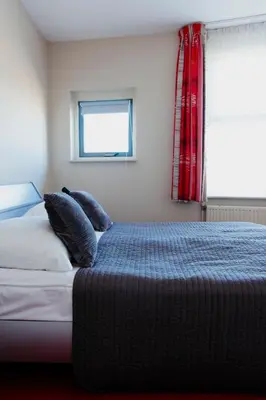 a bedroom with a bed with two pillows and a window at Appartement Spoorklokken in Bergen aan Zee