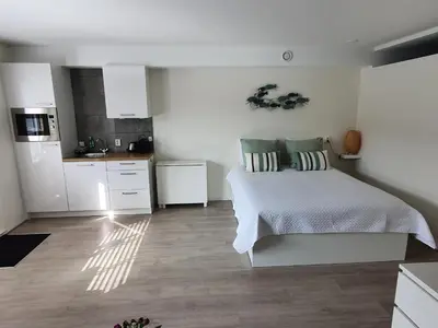 a white bedroom with a bed and a kitchen at Studio Noordzee in Zandvoort