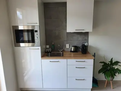 a kitchen with white cabinets and a microwave at Studio Noordzee in Zandvoort
