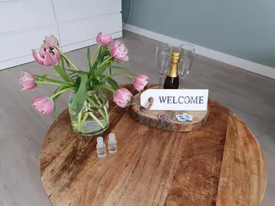 a table with a vase of flowers and a bottle of wine at Studio Noordzee in Zandvoort