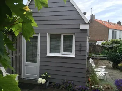 a gray house with a white door and a patio at Beach House Arina in Egmond aan Zee