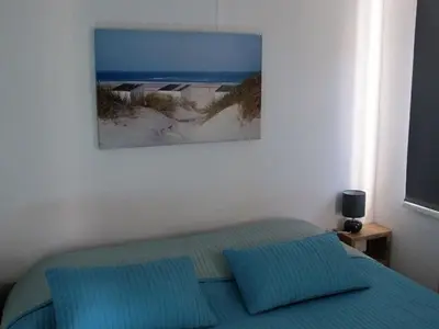 a bedroom with a bed with blue pillows and a painting at Beach House Arina in Egmond aan Zee