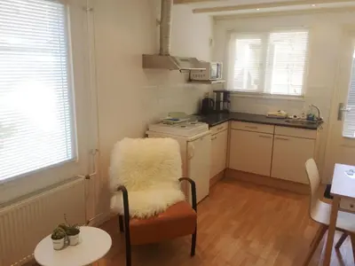 a kitchen with a table and a chair with a white furry seat at Beach House Arina in Egmond aan Zee