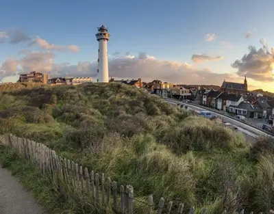 a lighthouse on top of a hill with a fence at Beach House Arina in Egmond aan Zee