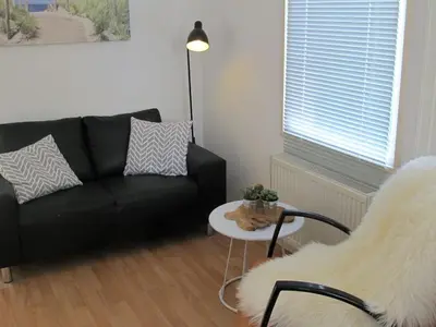 a living room with a black couch and a table at Beach House Arina in Egmond aan Zee