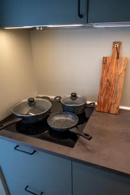 three pots and pans on a stove in a kitchen at Beach Bungalow Ohana - private garden - close to local Lake, Dunes and Beach in Noordwijkerhout