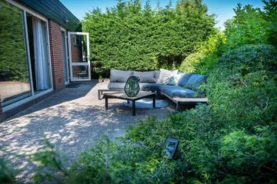 a patio with a couch and a coffee table at Beach Bungalow Ohana - private garden - close to local Lake, Dunes and Beach in Noordwijkerhout