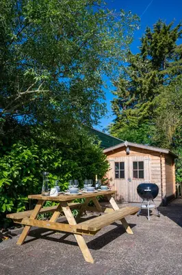 a wooden picnic table in front of a cabin at Beach Bungalow Ohana - private garden - close to local Lake, Dunes and Beach in Noordwijkerhout
