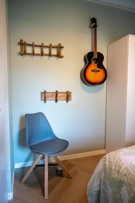 a blue chair in a room with a guitar on the wall at Beach Bungalow Ohana - private garden - close to local Lake, Dunes and Beach in Noordwijkerhout