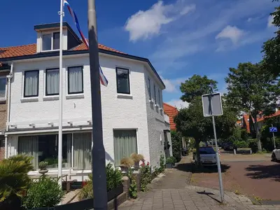 a white house with a flag on a pole at Deluxe STUDIO-appartement Heemstede Zandvoort in Heemstede