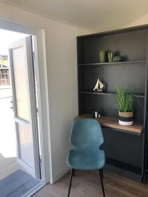 a desk with a blue chair next to a door at STRAND 21 hotelchalets in Zandvoort