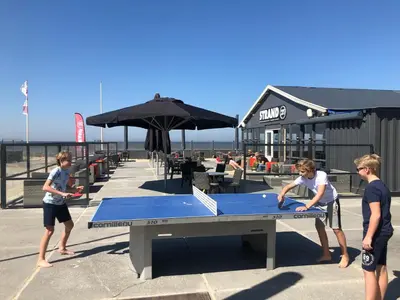 a group of people standing around a ping pong table at STRAND 21 hotelchalets in Zandvoort