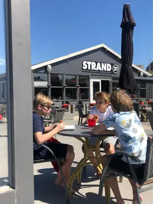three children sitting at a table with an umbrella at STRAND 21 hotelchalets in Zandvoort