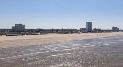 a view of a beach with buildings in the background at STRAND 21 hotelchalets in Zandvoort