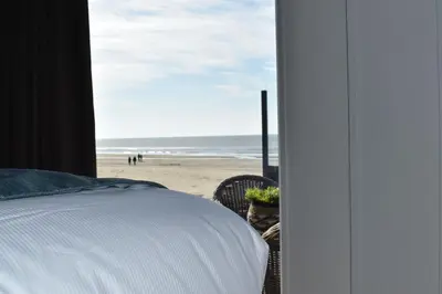 a bedroom with a bed and a view of the beach at STRAND 21 hotelchalets in Zandvoort