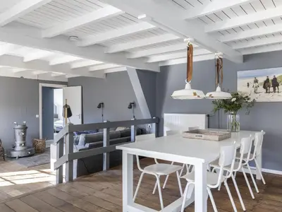 a dining room with a white table and chairs at Farmhouse in Groet near sea and forest in Groet