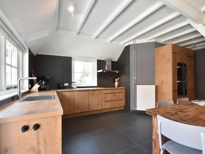 a large kitchen with wooden cabinets and a counter at Farmhouse in Groet near sea and forest in Groet
