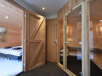 a bedroom with wood paneling and a sliding door at Farmhouse in Groet near sea and forest in Groet