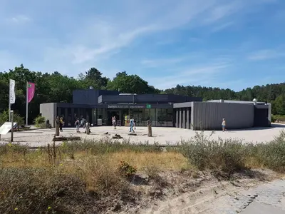 a building with people walking in front of it at Farmhouse in Groet near sea and forest in Groet