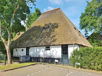 a thatch roofed building with a thatched roof at Farmhouse in Groet near sea and forest in Groet