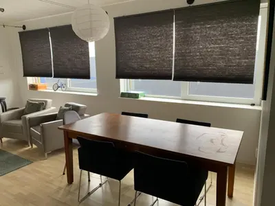 a dining room with a wooden table and black blinds at Apartments Zaanse Schans and Amsterdam in Wormer