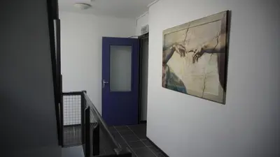 a hallway with a painting on the wall and a blue door at Apartments Zaanse Schans and Amsterdam in Wormer