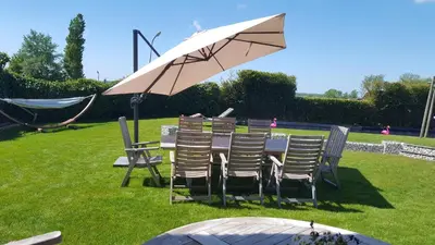 a table with chairs and an umbrella on the grass at Villa Pura Vida in Oud-Ade