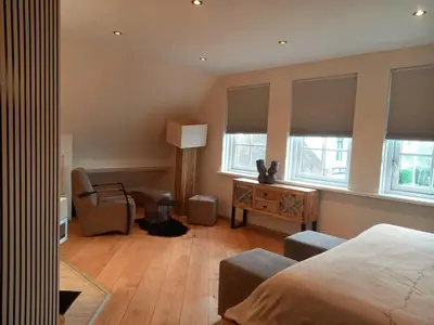 a bedroom with a bed and a desk and windows at Villa Pura Vida in Oud-Ade