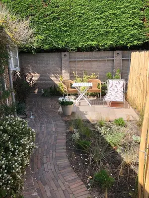 a patio with a table and chairs in a garden at Fabel aan Zee in Zandvoort