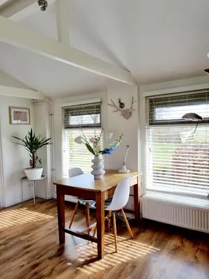 a dining room with a table and chairs and windows at ''Op Stok