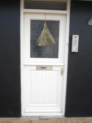 a white garage door with a broom on it at huisje de Strandjutter in Katwijk aan Zee