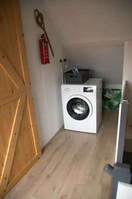 a laundry room with a washing machine and a door at huisje de Strandjutter in Katwijk aan Zee