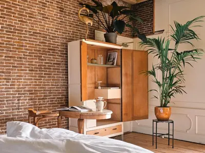 a bedroom with a bed and a wooden cabinet with plants at Eco Hotel Plantage Rococo in Velsen-Zuid