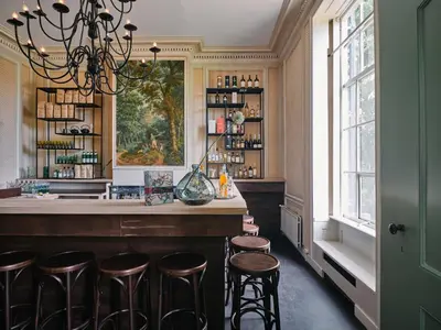 a bar with stools in a room with a window at Eco Hotel Plantage Rococo in Velsen-Zuid
