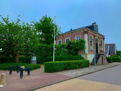 a large brick building with bushes in front of it at B&B 't Raethuys in Dirkshorn
