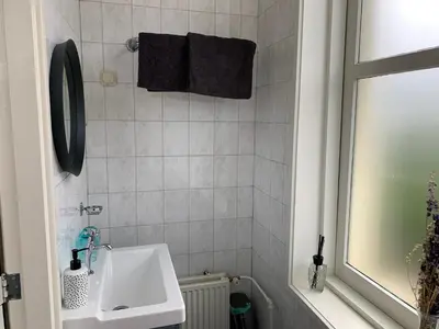 a white bathroom with a sink and a mirror at B&B 't Raethuys in Dirkshorn