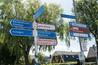 a street sign with many signs on a pole at B&B 't Raethuys in Dirkshorn