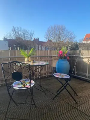 a patio with two chairs and a table and a vase with flowers at The Rock in Zandvoort