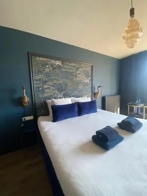 a bedroom with a large bed with two blue pillows at The Rock in Zandvoort