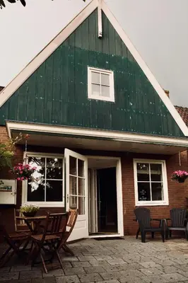 a green roofed house with chairs and a table at Slapen bij Jesse in Broek in Waterland