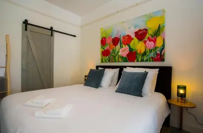 a bedroom with a white bed with a painting on the wall at Slapen bij Jesse in Broek in Waterland