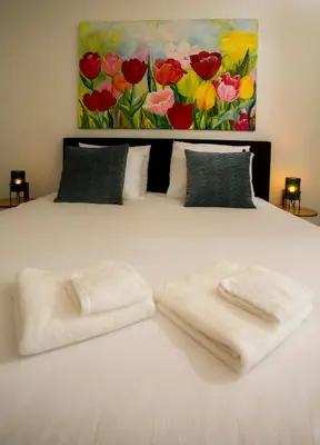a bed with two towels on it with a painting at Slapen bij Jesse in Broek in Waterland