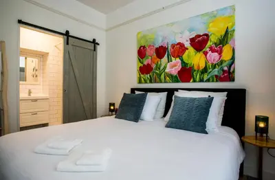 a bedroom with a white bed with a painting on the wall at Slapen bij Jesse in Broek in Waterland