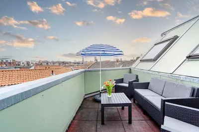 a patio with a table and an umbrella on a roof at Sunny Spacious Apartment De Bijenkorf in Zandvoort
