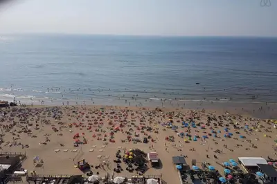 a crowd of people on a beach with umbrellas at Sunny Spacious Apartment De Bijenkorf in Zandvoort