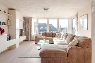 a living room with a couch and a large window at Sunny Spacious Apartment De Bijenkorf in Zandvoort