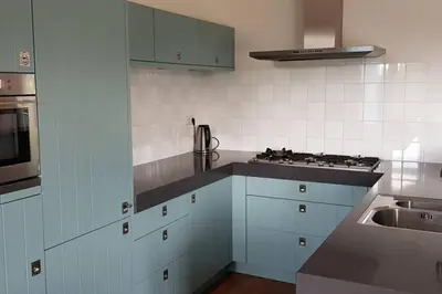 a kitchen with blue cabinets and a stove top oven at The Blue House - Luxurious Waterfront Villa Zeewolde in Zeewolde