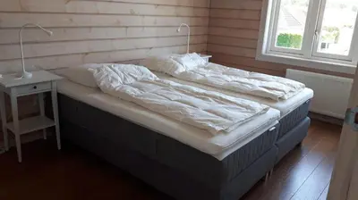 a bed with white sheets and a nightstand next to a window at The Blue House - Luxurious Waterfront Villa Zeewolde in Zeewolde