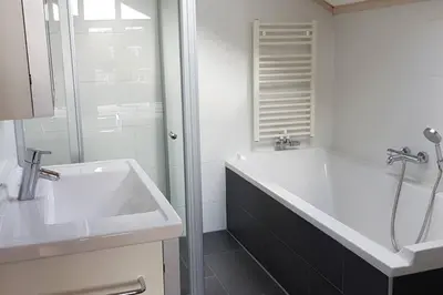 a white bathroom with a sink and a shower at The Blue House - Luxurious Waterfront Villa Zeewolde in Zeewolde